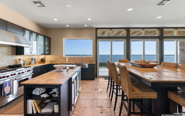 kitchen featuring backsplash, a water view, a center island, double oven range, and plenty of natural light