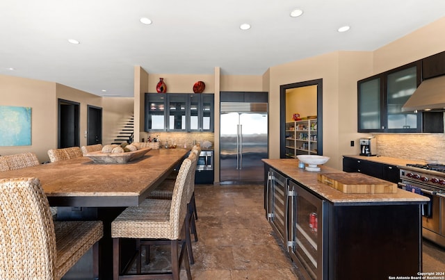 kitchen featuring a breakfast bar, tasteful backsplash, built in appliances, beverage cooler, and a center island