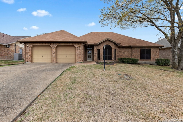 ranch-style home featuring a front lawn, a garage, and central AC unit