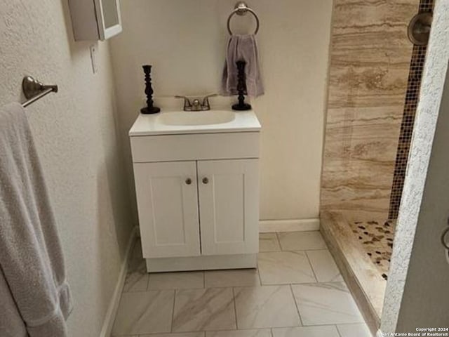 bathroom with a shower, vanity, and tile flooring