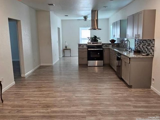 kitchen with ceiling fan, sink, hardwood / wood-style floors, appliances with stainless steel finishes, and wall chimney exhaust hood