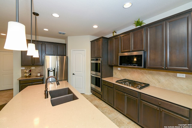 kitchen featuring decorative light fixtures, backsplash, light tile flooring, appliances with stainless steel finishes, and sink