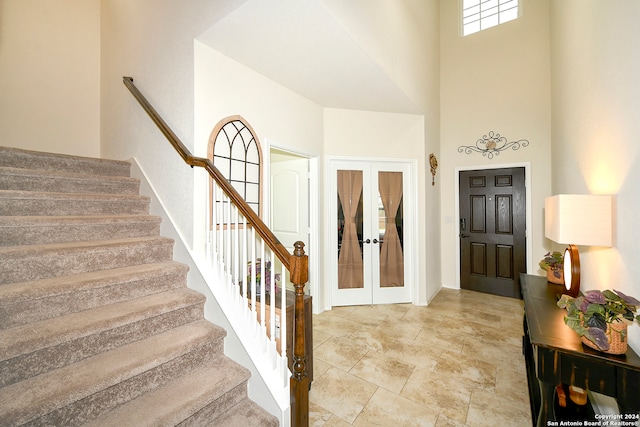 foyer with a high ceiling, french doors, and light tile floors