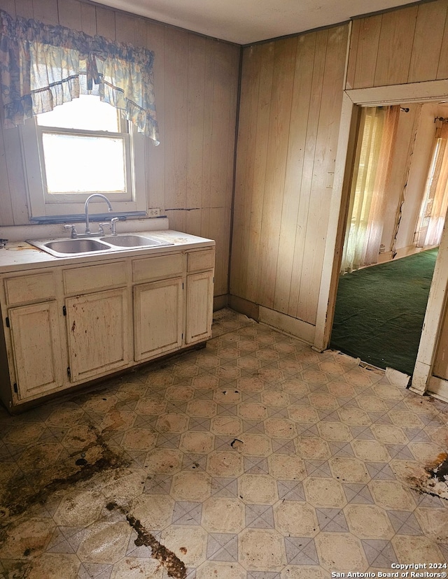 kitchen featuring wood walls, light tile floors, and sink