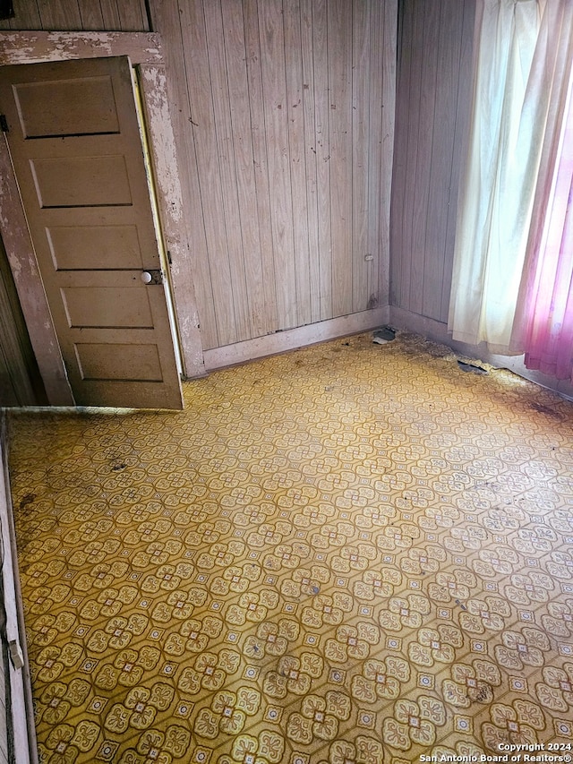 tiled empty room featuring wooden walls