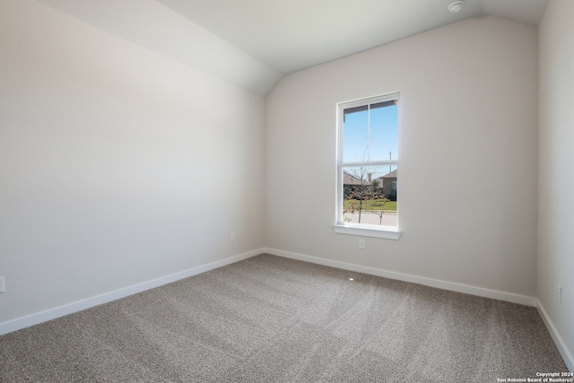 carpeted spare room featuring vaulted ceiling