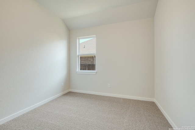 carpeted spare room featuring lofted ceiling