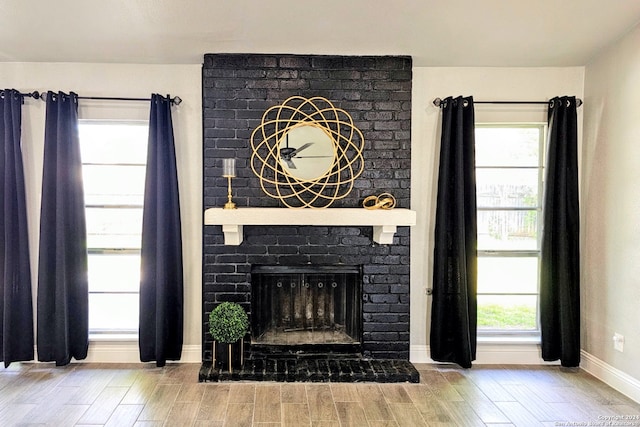 unfurnished living room featuring brick wall, a brick fireplace, and light wood-type flooring