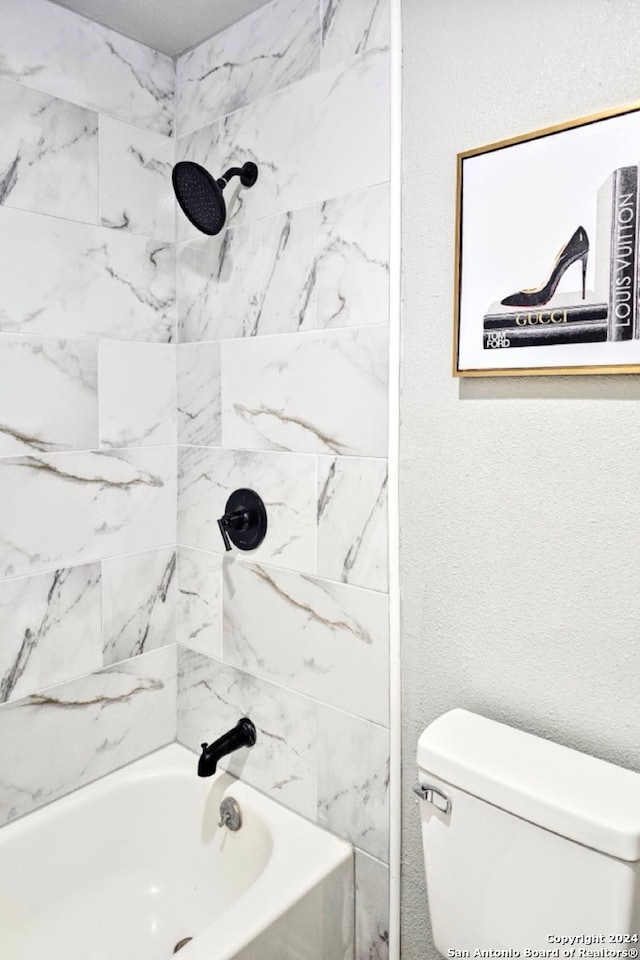 bathroom with tiled shower / bath combo and toilet