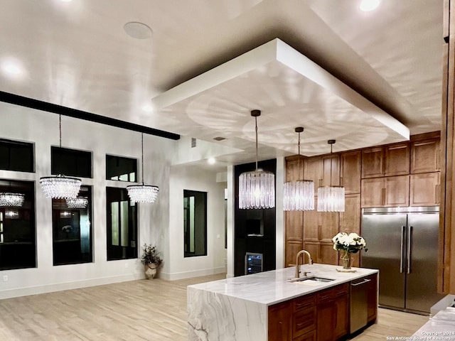 kitchen with a notable chandelier, light stone counters, light hardwood / wood-style floors, decorative light fixtures, and built in refrigerator