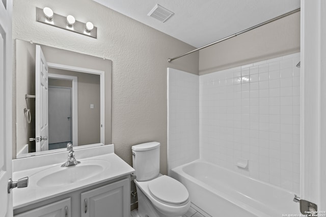 full bathroom featuring vanity, tiled shower / bath combo, toilet, and a textured ceiling