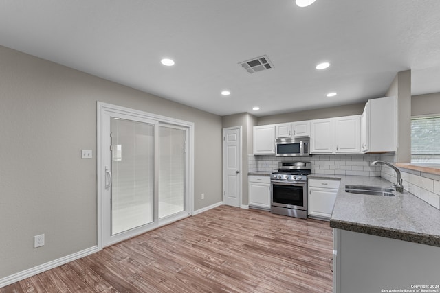 kitchen with appliances with stainless steel finishes, light hardwood / wood-style floors, white cabinetry, and sink