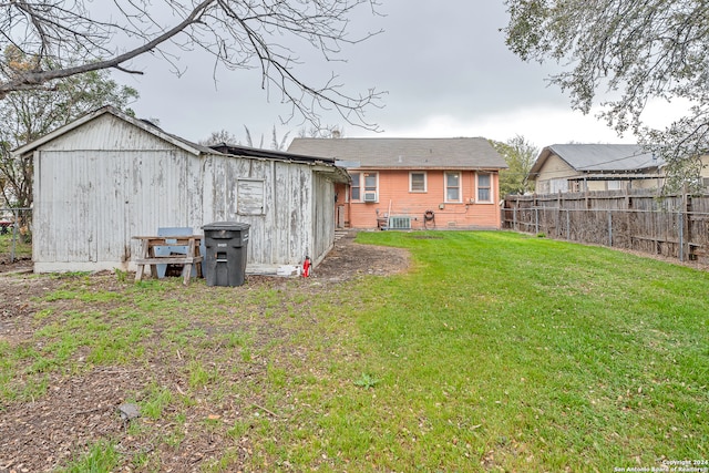 rear view of house featuring central AC unit and a lawn