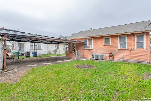 back of property with a carport, central AC, and a lawn