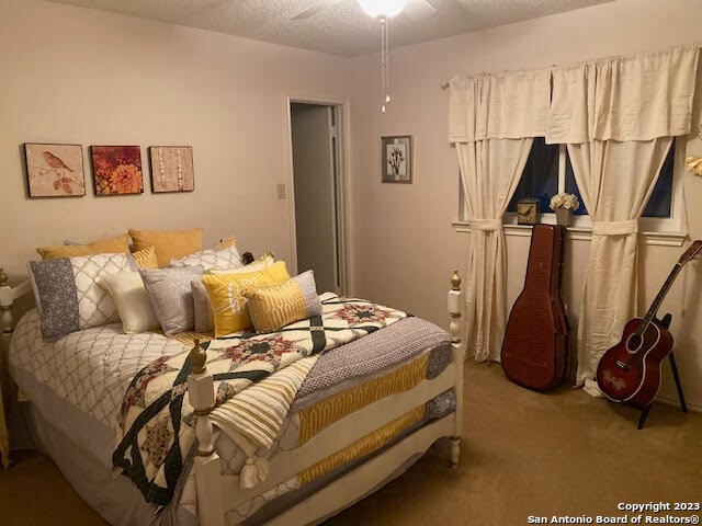 bedroom featuring ceiling fan, a textured ceiling, and carpet flooring