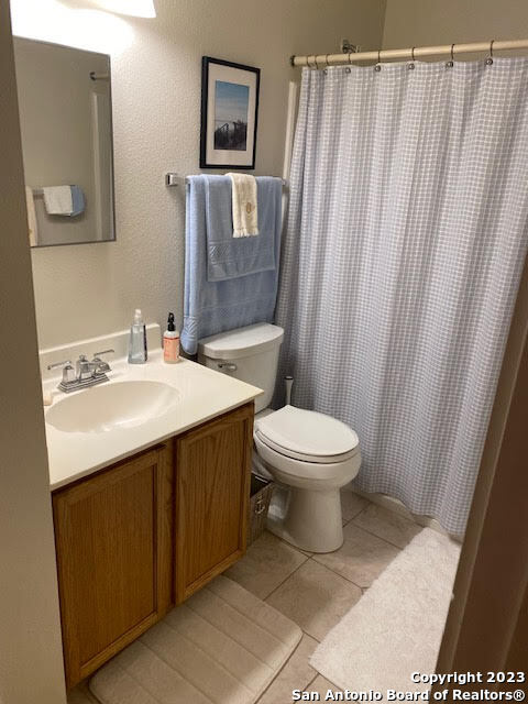 bathroom with tile patterned flooring, curtained shower, vanity, and toilet