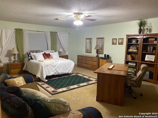 bedroom featuring ceiling fan, a textured ceiling, and light carpet