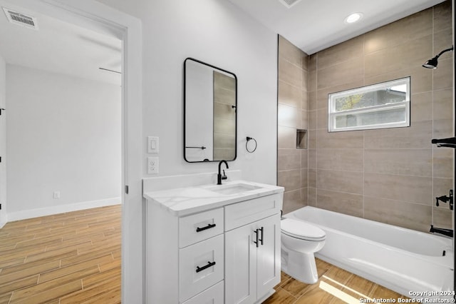 full bathroom with hardwood / wood-style floors, toilet, vanity, and tiled shower / bath combo