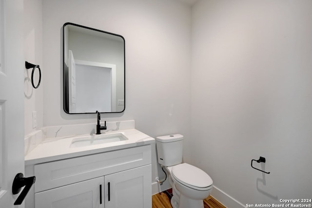 bathroom with large vanity, toilet, and wood-type flooring