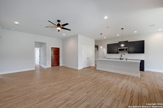 unfurnished living room featuring ceiling fan, sink, and light hardwood / wood-style floors