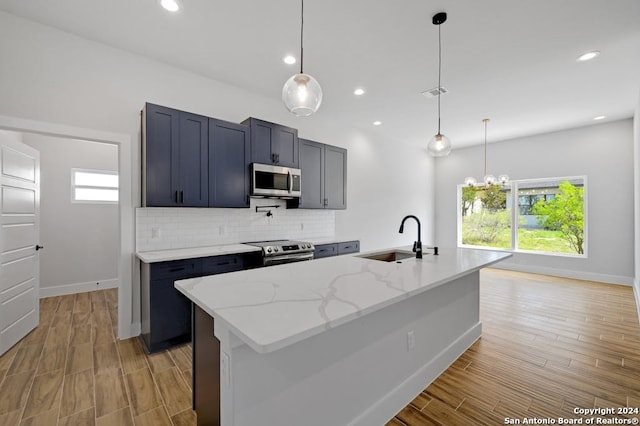 kitchen with decorative light fixtures, backsplash, appliances with stainless steel finishes, sink, and light stone counters