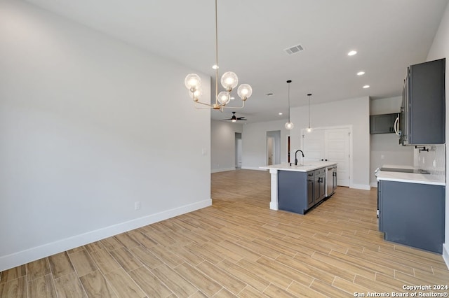 kitchen with pendant lighting, sink, a center island with sink, light hardwood / wood-style floors, and tasteful backsplash