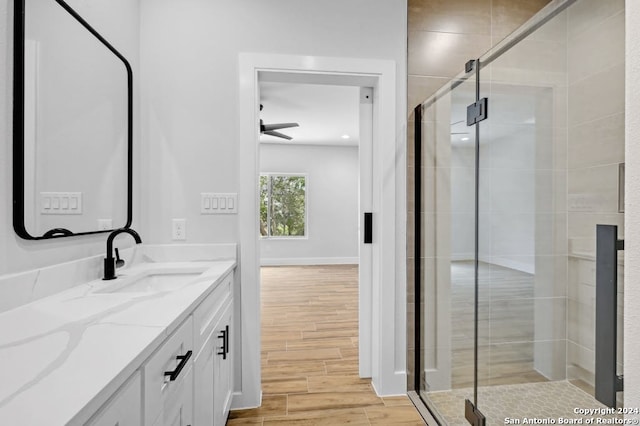 bathroom featuring a shower with shower door, oversized vanity, ceiling fan, and hardwood / wood-style flooring