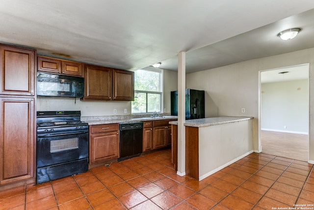 kitchen with dark tile floors, sink, and black appliances