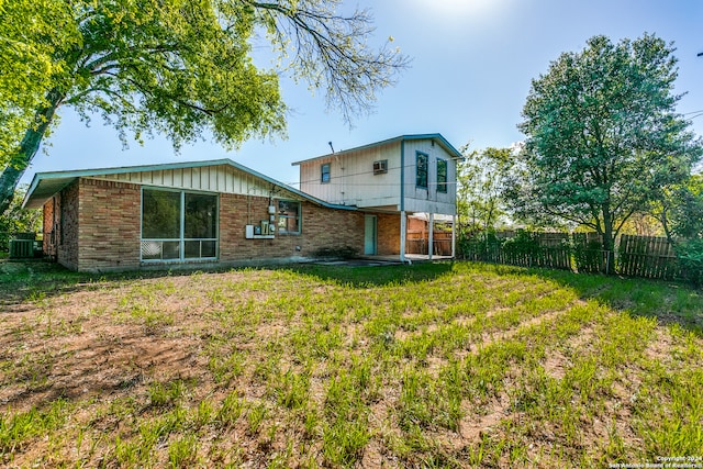 rear view of property with central AC unit and a yard