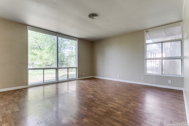 spare room with a healthy amount of sunlight and dark wood-type flooring