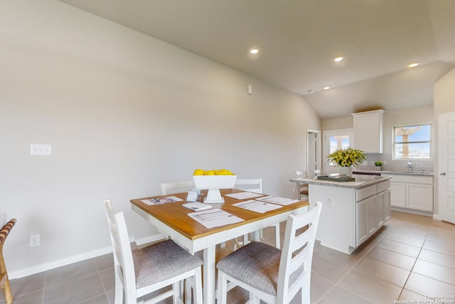 dining space featuring sink, light tile patterned floors, and lofted ceiling