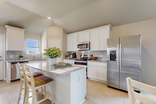 kitchen with white cabinets, stainless steel appliances, and lofted ceiling