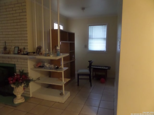 interior space featuring a brick fireplace and light tile floors