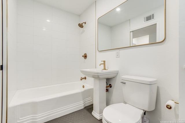 bathroom with toilet, tile floors, and tiled shower / bath