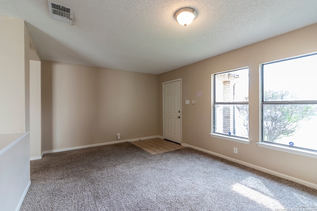 carpeted empty room with a textured ceiling