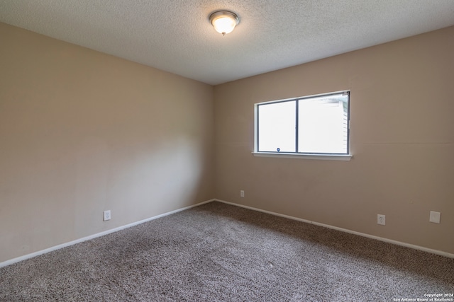 carpeted empty room with a textured ceiling