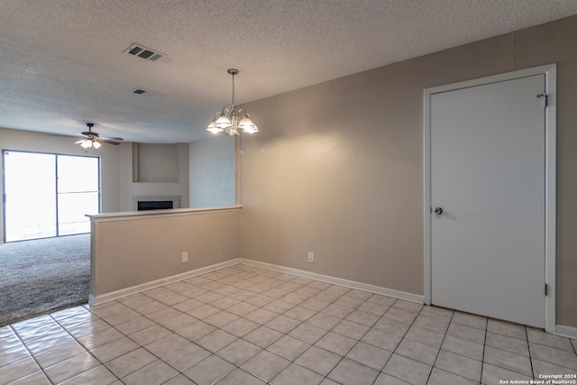 carpeted spare room featuring a textured ceiling and ceiling fan with notable chandelier