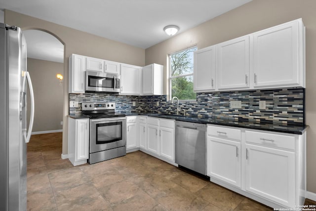 kitchen with light tile floors, tasteful backsplash, appliances with stainless steel finishes, white cabinets, and sink