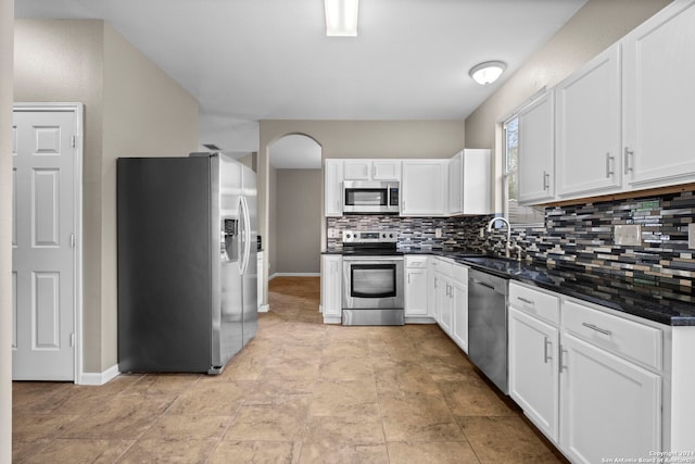 kitchen featuring sink, appliances with stainless steel finishes, light tile flooring, tasteful backsplash, and white cabinetry