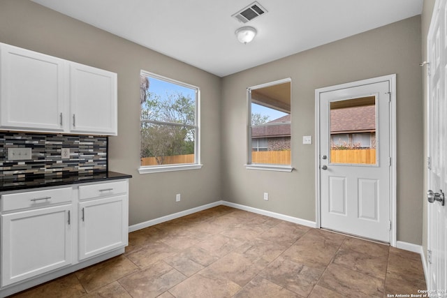 kitchen with white cabinets, light tile flooring, and tasteful backsplash