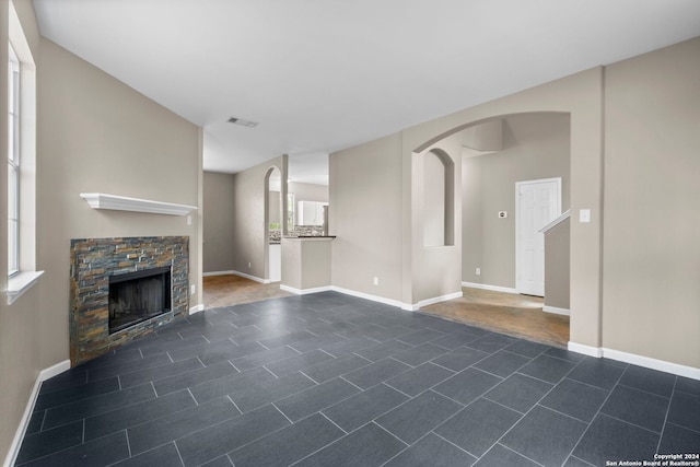 unfurnished living room featuring dark tile floors and a fireplace