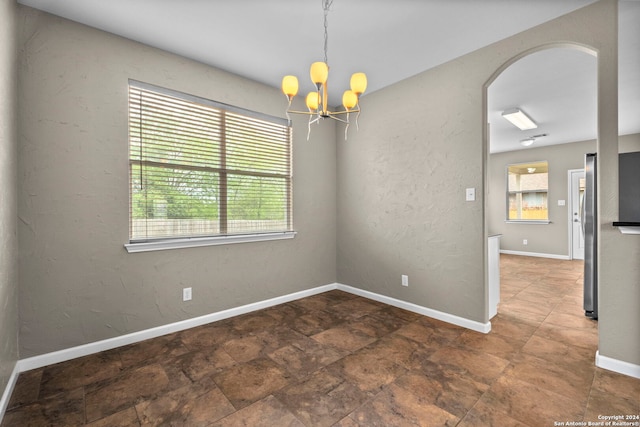 tiled spare room with a notable chandelier and plenty of natural light