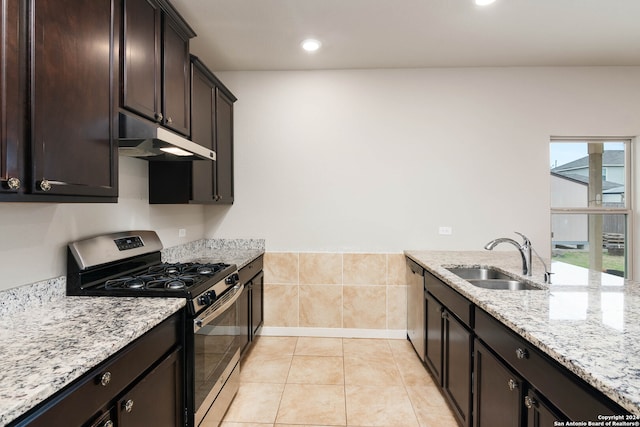 kitchen featuring appliances with stainless steel finishes, sink, light tile floors, light stone counters, and dark brown cabinets