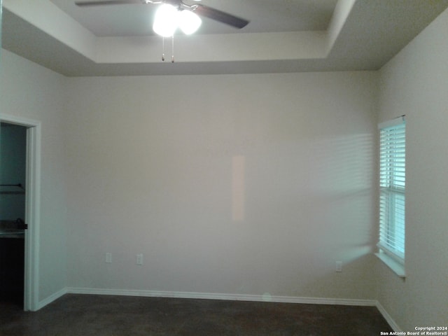 carpeted empty room featuring a raised ceiling and ceiling fan