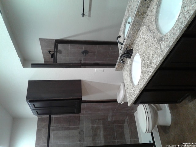 bathroom with dual vanity, tile flooring, and toilet