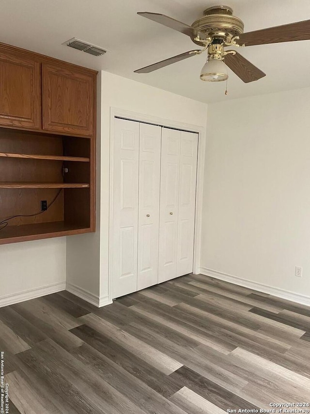 unfurnished bedroom with ceiling fan, a closet, and dark wood-type flooring