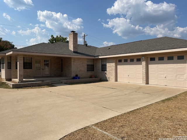 single story home featuring covered porch, french doors, and a garage