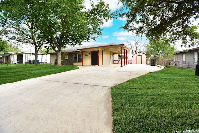 ranch-style home with a storage unit, a front yard, and a carport