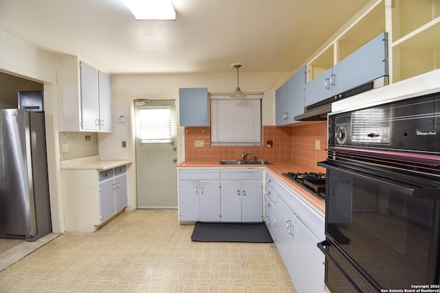 kitchen with tasteful backsplash, light tile floors, sink, black appliances, and hanging light fixtures