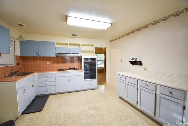 kitchen featuring light tile flooring, gas stovetop, backsplash, sink, and double oven